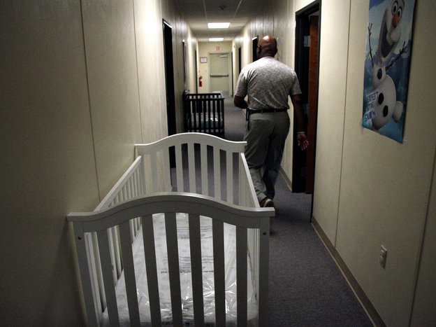 A federal employee walks past cribs inside the Artesia detention center in June.