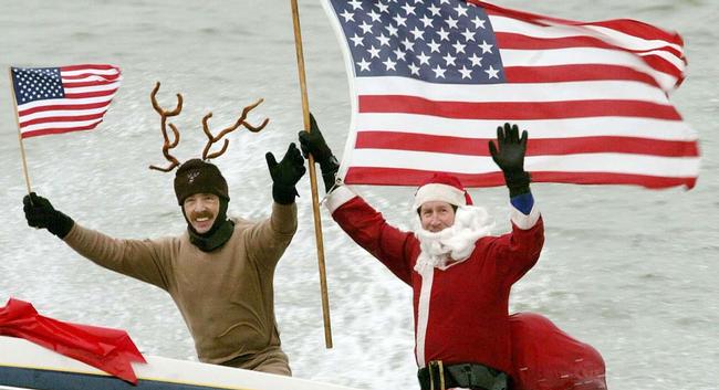 ARLINGTON, VA - DECEMBER 24:  Dressed as Santa Claus, Kerry Nistel (R) holds an American flag after water-skiing along the Potomac River near the Washington Monument December 24, 2003 in Arlington, Virginia. This is the 18th year Nistel has dressed as Santa and water-skied on Christmas Eve.  (Photo by Mark Wilson/Getty Images)